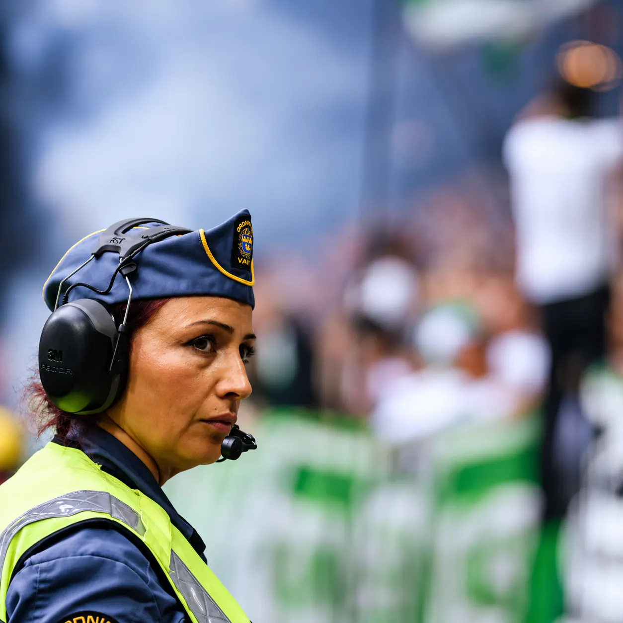 Ordningsvakt från Sweden Secure AB med hörselskydd och radio vid publiken